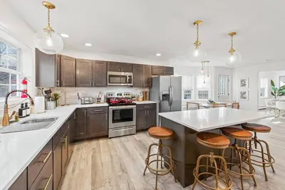 a kitchen with stainless steel appliances and wooden cabinets at Boho Haven Hideaway - Walk to Pool,Theater,Arcades, Firepit, Lake Access in Thornhurst