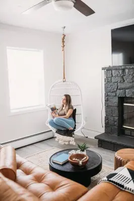a woman sitting in a swing reading a book at Boho Haven Hideaway - Walk to Pool,Theater,Arcades, Firepit, Lake Access in Thornhurst