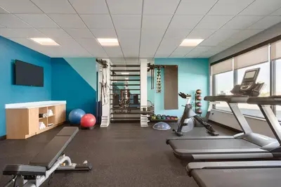 a gym with blue walls and tread machines at avid hotel Harrisburg NE - Hershey Area by IHG in Harrisburg