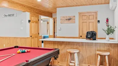 a pool table in a room with a counter and stools at Bluejay Getaway by AvantStay Private Lake Cabin • Hot Tub Game Room Walk to Lake in Albrightsville