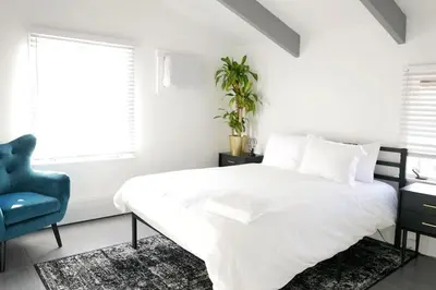 a white bedroom with a bed and a blue chair at 10 guest Ski Chalet Pools Golf Ski Hike in Vernon Township
