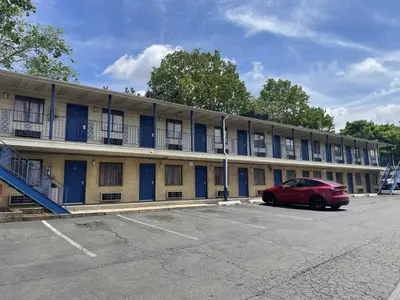 a building with a red car parked in a parking lot at Budget Inn - Elizabeth, NJ in Elizabeth