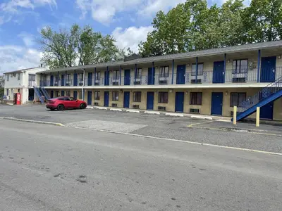 a red car parked in front of a building at Budget Inn - Elizabeth, NJ in Elizabeth