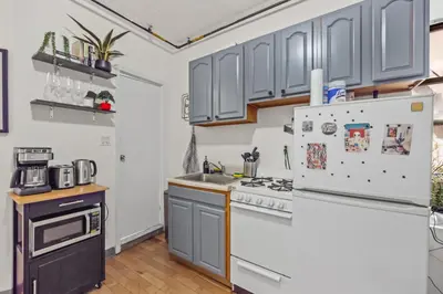 a kitchen with gray cabinets and a refrigerator at Tranquil Haven 1-Bdr Apt in Downtown Manhattan's Union Square in New York