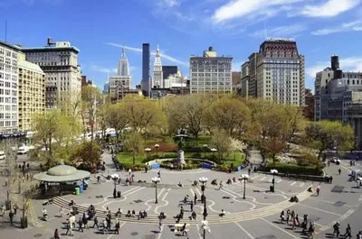 a group of people walking around a park in a city at Tranquil Haven 1-Bdr Apt in Downtown Manhattan's Union Square in New York