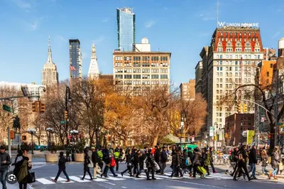 a group of people crossing a street in a city at Tranquil Haven 1-Bdr Apt in Downtown Manhattan's Union Square in New York