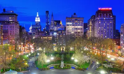 a city skyline at night with a fountain in a park at Tranquil Haven 1-Bdr Apt in Downtown Manhattan's Union Square in New York