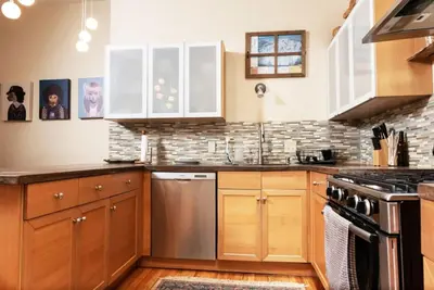 a kitchen with wooden cabinets and stainless steel appliances at MASSiVE Bohemian Oasis in Philly 5 Bdrm Sleeps 12 in Philadelphia