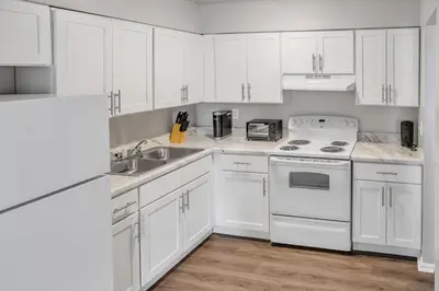 a white kitchen with white cabinets and a sink at Spacious Retreat I Balcony I Parking I Chateau in Wilmington