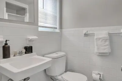 a white bathroom with a toilet and a sink at Spacious Retreat I Balcony I Parking I Chateau in Wilmington