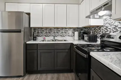 a kitchen with white cabinets and a stainless steel refrigerator at Chateau 506 Stunning In Wilmington, Free Parking! in Wilmington