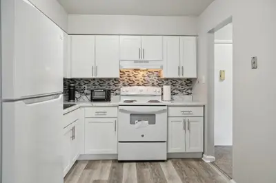 a white kitchen with white cabinets and a stove at Historic Charm Meets Modern Comfort The Chateau in Wilmington