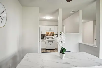 a white kitchen with a table with a vase of flowers at Historic Charm Meets Modern Comfort The Chateau in Wilmington