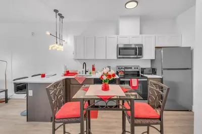 a kitchen with a table and chairs and a kitchen with white cabinets at Royal Oasis Indoor Pool, FREE Parking, Near NYC in Elizabeth