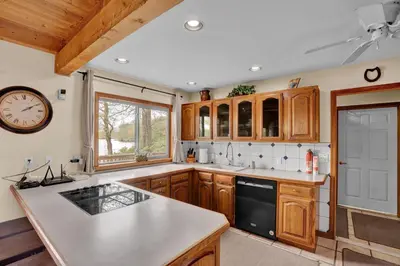 a kitchen with wooden cabinets and a clock on the wall at Lakefront Family Home, Kayaks, Hot Tub, Fireplace in Lake Ariel