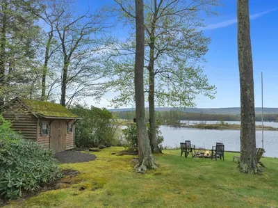a cabin with a bench and a picnic table next to a lake at Lakefront Family Home, Kayaks, Hot Tub, Fireplace in Lake Ariel
