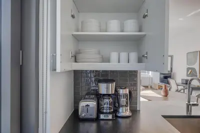 a kitchen counter with a coffee maker and plates at Blueground Hudson Yards gym rock wall arcade NYC-1453 in New York