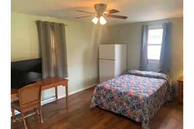 a bedroom with a bed and a desk and a television at Werry's Cottages and Pub By OYO East Stroudsborg - Weekly Stays in East Stroudsburg