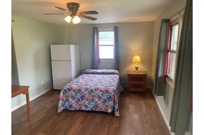 a bedroom with a bed and a white refrigerator at Werry's Cottages and Pub By OYO East Stroudsborg - Weekly Stays in East Stroudsburg