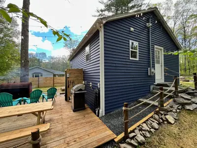a blue tiny house with a wooden deck at Bear Run Bungalow in Hawley