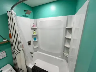 a bathroom with a white tub and a green wall at Bear Run Bungalow in Hawley