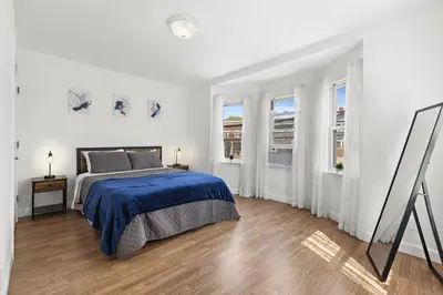 a white bedroom with a bed and two windows at Comfy Cozy retreat - NYC & NWK w free parking in Bayonne