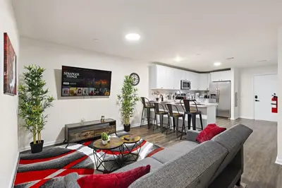 a living room with a couch and a table and a kitchen at Family & Traveler Haven - NYC & NWK w/free parking in Newark