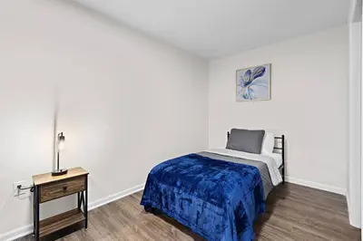a white bedroom with a bed and a table at Home Sweet Home - near NWK & NYC w/free parking in Newark
