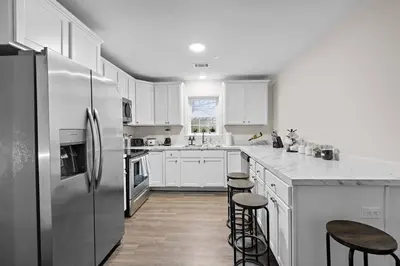 a kitchen with white cabinets and a stainless steel refrigerator at Home Sweet Home - near NWK & NYC w/free parking in Newark