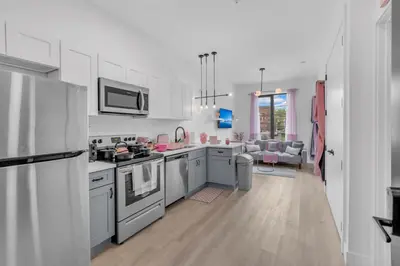 a kitchen with stainless steel appliances and a living room at Pink Heaven Indoor Pool, FREE Parking, Near NYC in Elizabeth