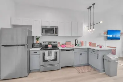a kitchen with white cabinets and a stainless steel refrigerator at Pink Heaven Indoor Pool, FREE Parking, Near NYC in Elizabeth
