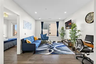 a living room with a blue couch and a desk at Cozy Stylish retreat - NYC & NWK w free parking in Bayonne