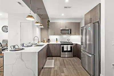 a kitchen with stainless steel appliances and wooden cabinets at Cozy Stylish retreat - NYC & NWK w free parking in Bayonne