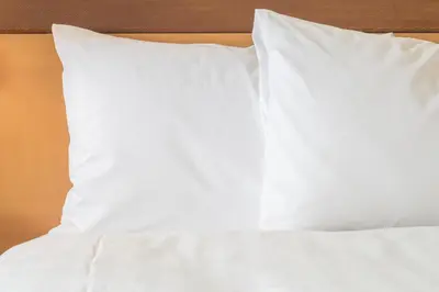 a bed with white sheets and pillows on it at Candlewood Suites Pittston by IHG in Pittston
