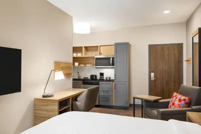a room with a bed and a desk and a kitchen at Candlewood Suites Pittston by IHG in Pittston