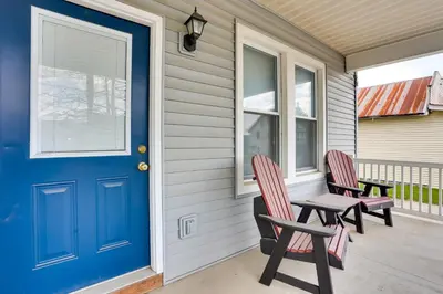 a porch with two chairs and a blue door at Amish Country Townhome Near Hiking and Fly Fishing! in Loganton