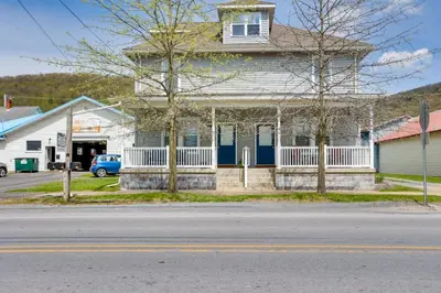a white house with a blue front porch at Amish Country Townhome Near Hiking and Fly Fishing! in Loganton