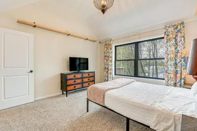 a bedroom with a bed and a tv and a window at Lakefront Long Pond Home with Wraparound Deck! in Long Pond
