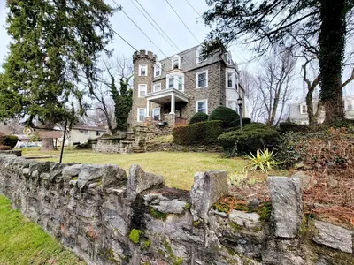 a stone fence in front of a large house at 1 Bedroom 1 Bath Apartment In Melrose Park in Elkins Park