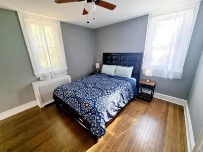 a bedroom with a bed with a blue comforter and two windows at 1 Bedroom 1 Bath Apartment In Melrose Park in Elkins Park