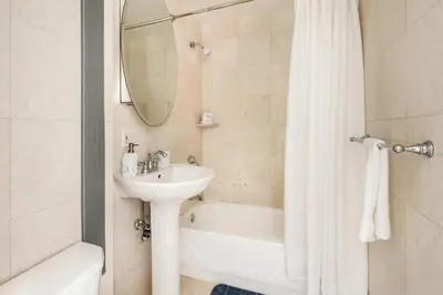 a bathroom with a sink and a tub and a mirror at 73-318 New Studio UWS Doorman Gym in New York