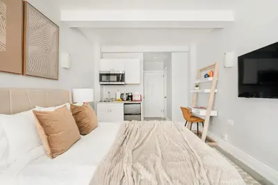 a white bedroom with a bed and a kitchen at 73-1503 Newly Reno Studio UWS Doorman Gym Laundry in New York