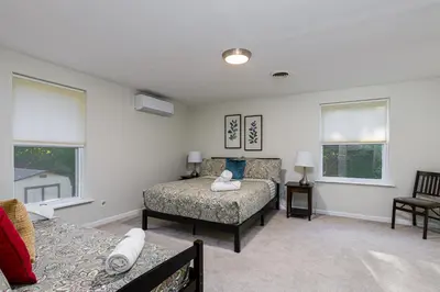 a bedroom with a bed and a couch and windows at 5mi to Big Boulder Hot tub Patio Firepit Fast WiFi in Blakeslee