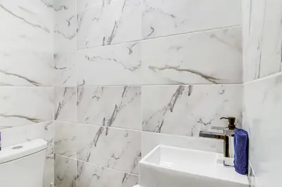 a bathroom with white marble walls and a sink at Hot Tub and Lake Beach Access Tobyhanna Retreat! in Tobyhanna