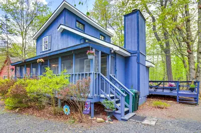 a blue tiny house in the middle of the woods at Hot Tub and Lake Beach Access Tobyhanna Retreat! in Tobyhanna