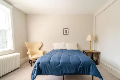 a bedroom with a blue bed and a chair at Victorian Home Sleeps 10 Fenced 4BR Full Kitchen Steps2 YCP in York