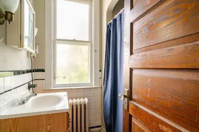 a bathroom with a sink and a window and a wooden door at Victorian Home Sleeps 10 Fenced 4BR Full Kitchen Steps2 YCP in York