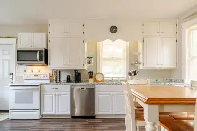 a kitchen with white cabinets and a wooden table at Victorian Home Sleeps 10 Fenced 4BR Full Kitchen Steps2 YCP in York