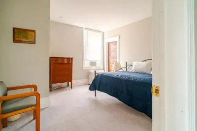 a bedroom with a bed and a chair and a window at Victorian Home Sleeps 10 Fenced 4BR Full Kitchen Steps2 YCP in York