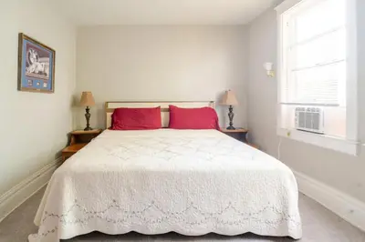 a bedroom with a large white bed with red pillows at Victorian Home Sleeps 10 Fenced 4BR Full Kitchen Steps2 YCP in York